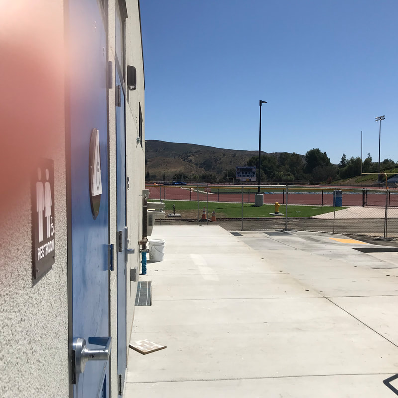 Photo of All Gender restroom in field house with football field in the background to  show relative location.